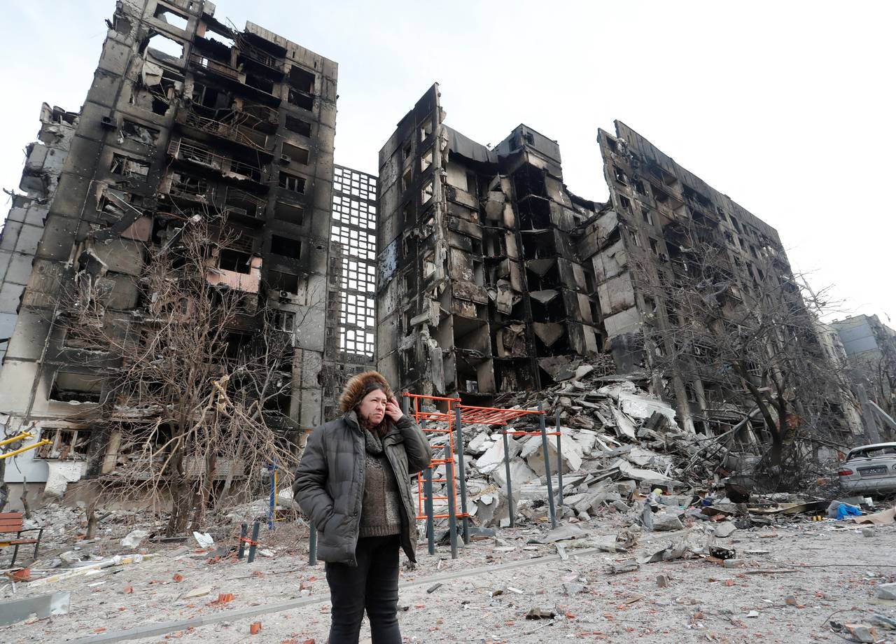 Nurse Svetlana Savchenko stands next to the destroyed building where her apartment was in Mariupol