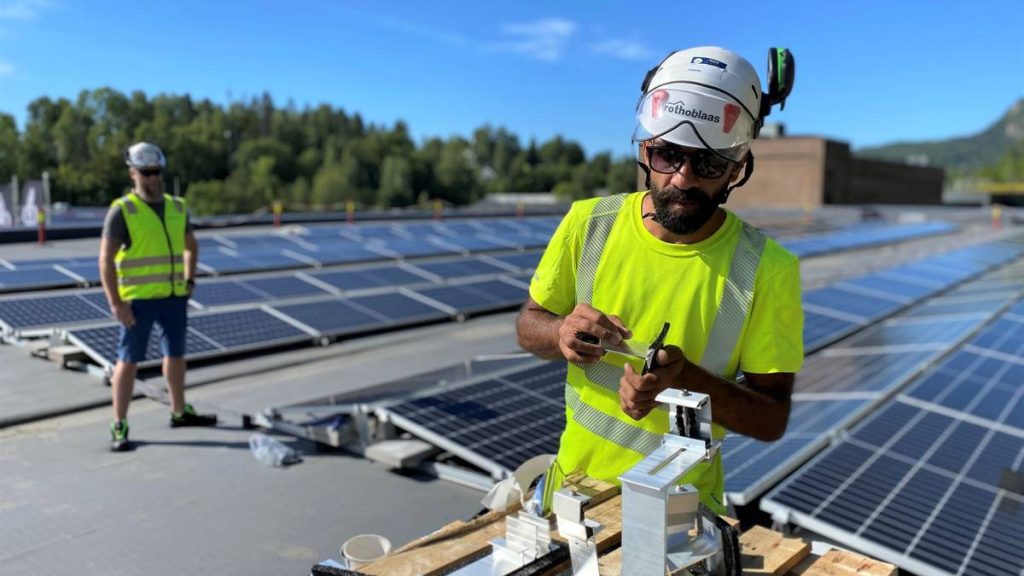 Farid Annan og Håvard Fjellheim (bak) under installering av et solcelleanlegg på taket av et forretningsbygg i Asker.